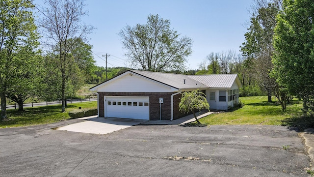 view of front of home with fence, an attached garage, driveway, a front yard, and metal roof