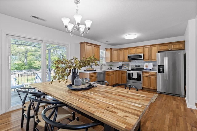 kitchen with tasteful backsplash, a chandelier, stainless steel appliances, light countertops, and visible vents
