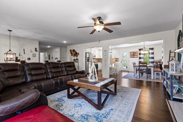 living area featuring dark wood-style floors and ceiling fan with notable chandelier