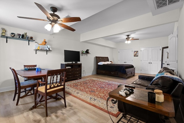 bedroom featuring multiple closets, visible vents, light wood-type flooring, and baseboards