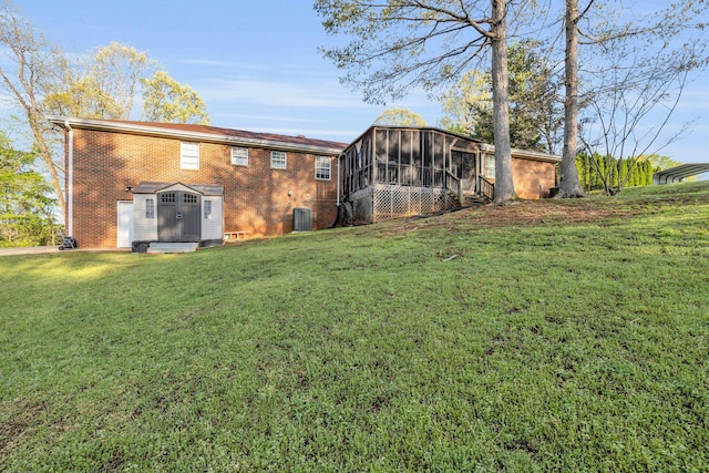 6434 Waconda Point Rd, Harrison, TN 37341 - rear view of house with an outdoor structure, brick siding, central AC unit, a sunroom, and a lawn