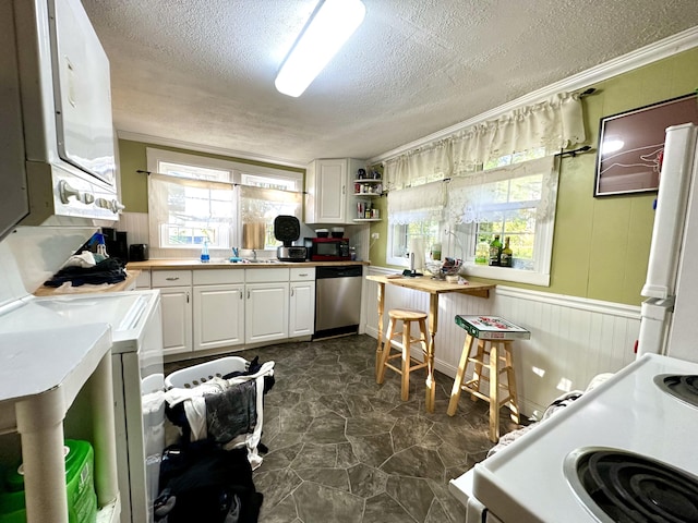 kitchen featuring stacked washer / dryer, a sink, white appliances, a textured ceiling, and white cabinetry