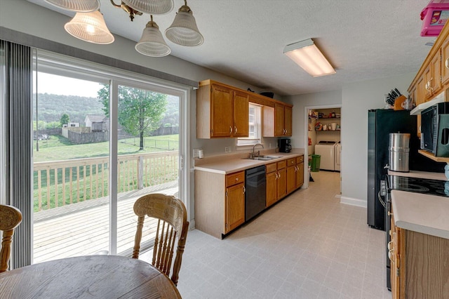 kitchen featuring light countertops, a sink, washer and clothes dryer, and black appliances
