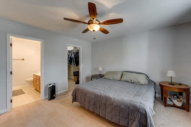 bedroom with a closet, a spacious closet, baseboards, and light carpet