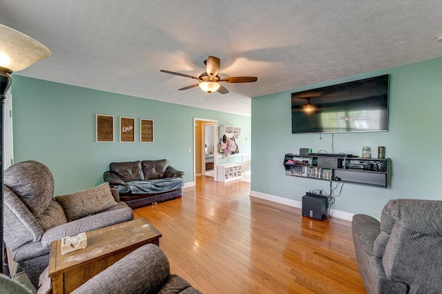 living area featuring baseboards, a ceiling fan, wood finished floors, and a textured ceiling