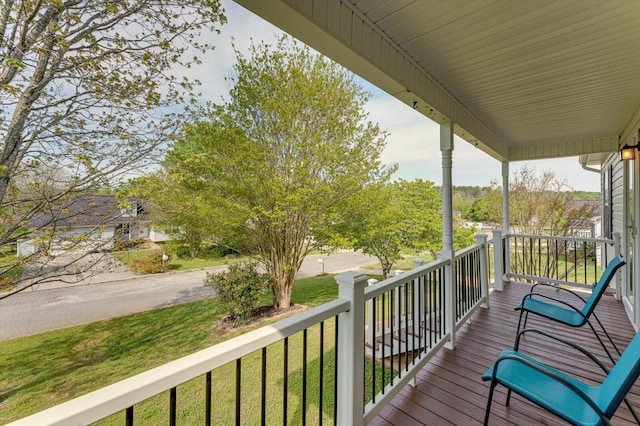 wooden terrace featuring a lawn and covered porch
