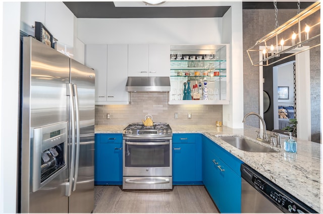 kitchen featuring light wood-type flooring, under cabinet range hood, blue cabinets, a sink, and appliances with stainless steel finishes
