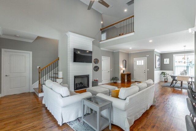 living room featuring stairway, visible vents, ornamental molding, and wood finished floors