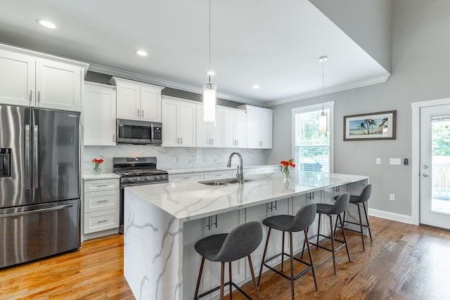 kitchen featuring stainless steel appliances, backsplash, ornamental molding, a sink, and white cabinetry