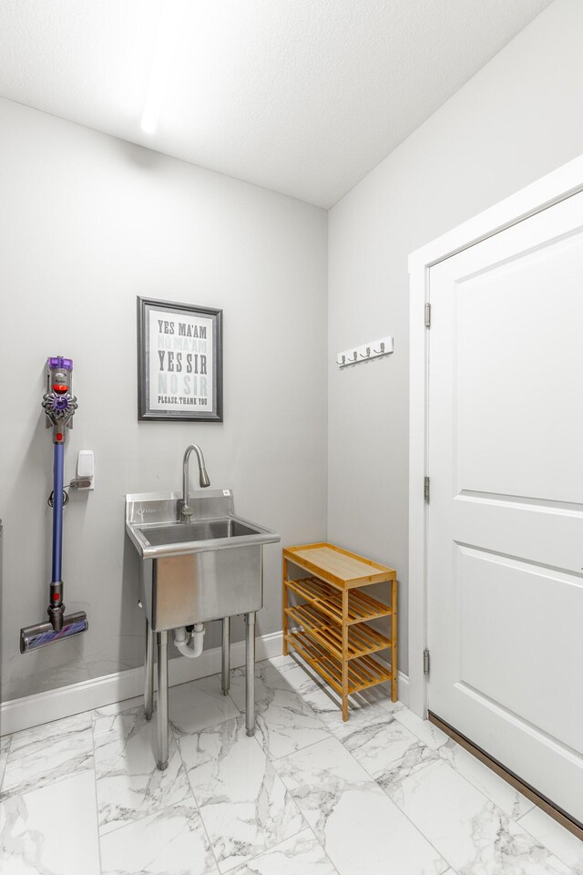 interior space with baseboards, marble finish floor, and a sink