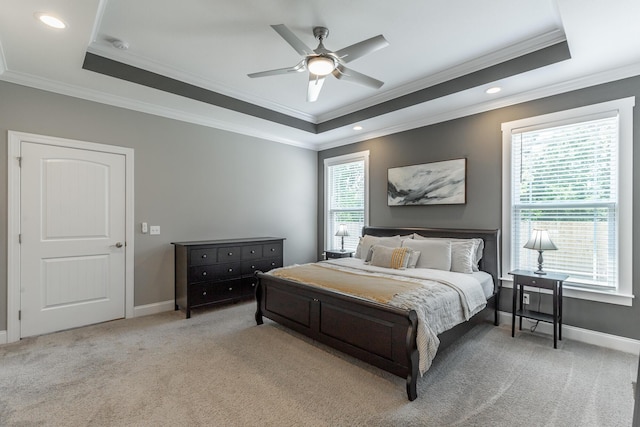 bedroom with light colored carpet, baseboards, crown molding, and a tray ceiling