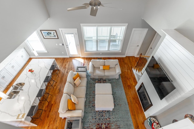 living room with ceiling fan, lofted ceiling, wood finished floors, and baseboards