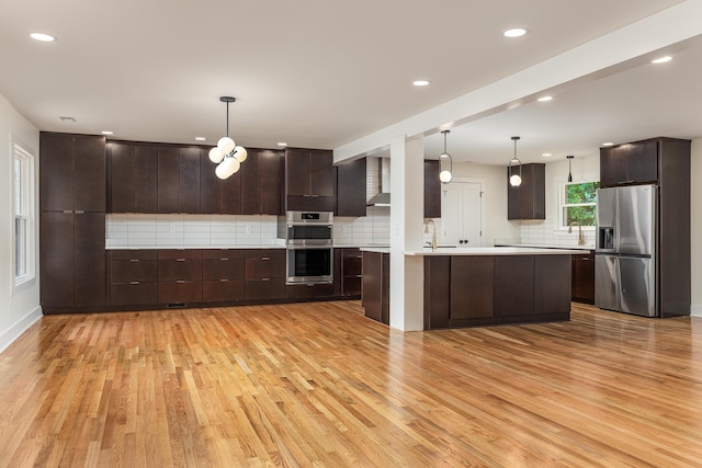kitchen with light countertops, appliances with stainless steel finishes, dark brown cabinets, backsplash, and light wood-style flooring