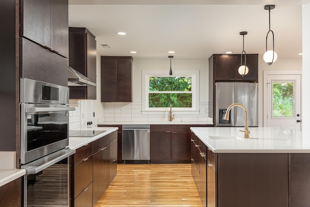 kitchen featuring tasteful backsplash, dark brown cabinets, appliances with stainless steel finishes, light countertops, and a sink