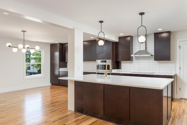 kitchen with light wood-style floors, decorative backsplash, light countertops, and dark brown cabinets