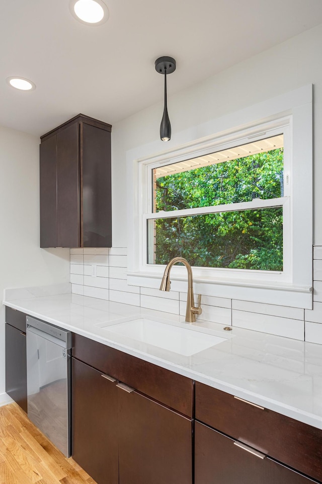 kitchen with tasteful backsplash, stainless steel dishwasher, a sink, and dark brown cabinets