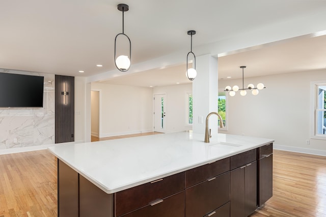 kitchen featuring open floor plan, light wood-style flooring, a sink, and a healthy amount of sunlight