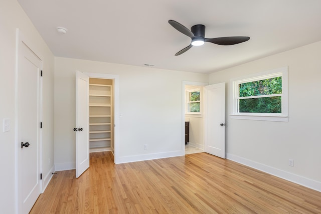 unfurnished bedroom featuring baseboards, light wood-style flooring, a ceiling fan, a walk in closet, and visible vents