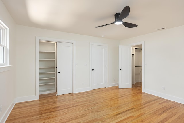 unfurnished bedroom featuring visible vents, baseboards, two closets, a ceiling fan, and light wood-style flooring