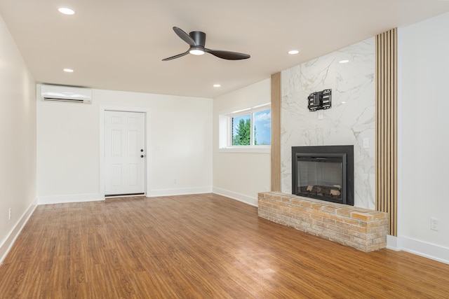 unfurnished living room featuring ceiling fan, a fireplace, recessed lighting, a wall mounted AC, and wood finished floors