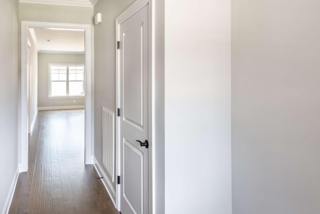 corridor with crown molding, dark wood-style flooring, baseboards, and visible vents