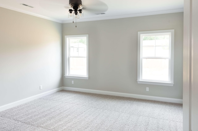 carpeted spare room featuring ceiling fan, baseboards, ornamental molding, and visible vents