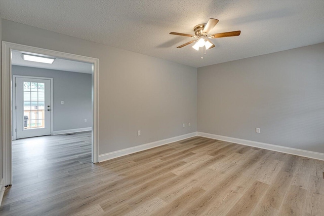 unfurnished room featuring light wood-style floors, baseboards, a ceiling fan, and a textured ceiling