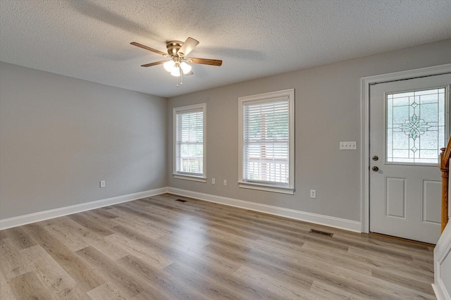 entryway with plenty of natural light, light wood-style floors, a textured ceiling, and ceiling fan