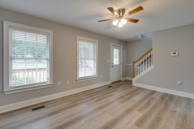 foyer entrance featuring light wood-style floors, plenty of natural light, visible vents, and a ceiling fan
