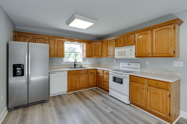 kitchen with light countertops, light wood-style floors, a sink, and white appliances