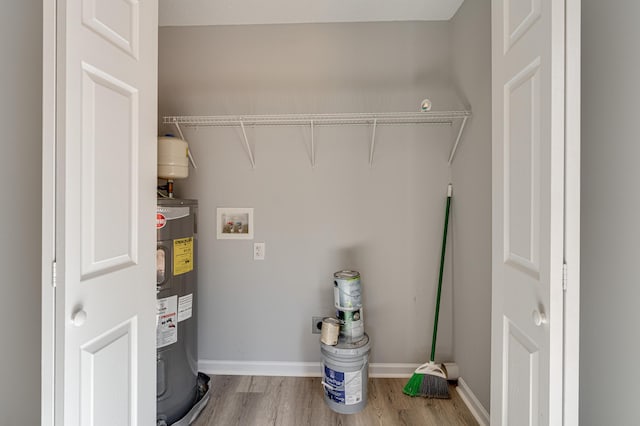 washroom with baseboards, laundry area, electric water heater, wood finished floors, and hookup for a washing machine