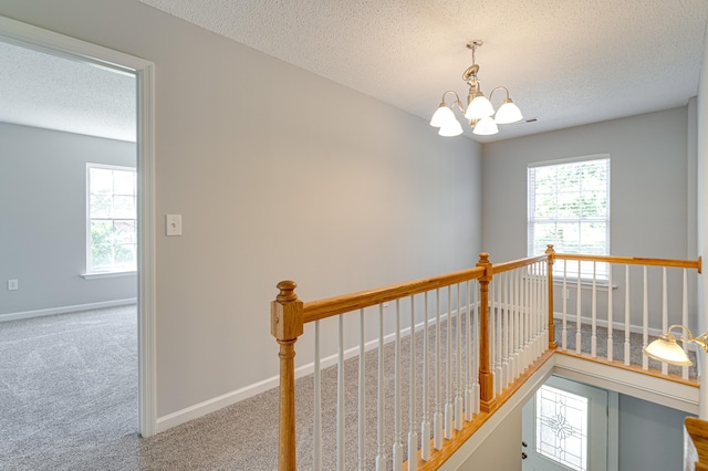 corridor featuring an upstairs landing and a textured ceiling