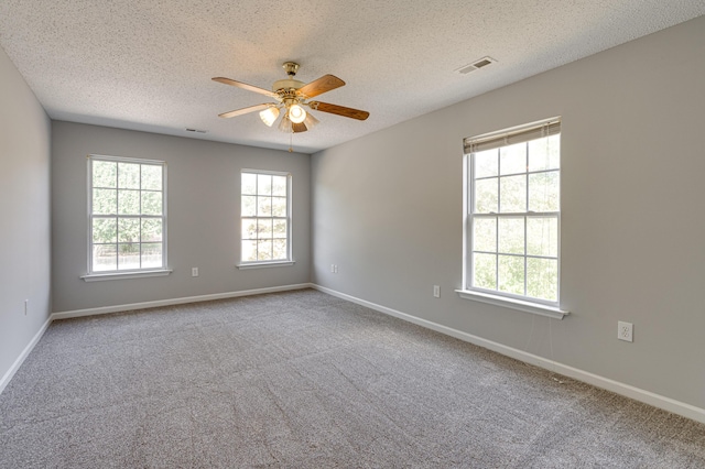 unfurnished room with a textured ceiling, a ceiling fan, visible vents, and a wealth of natural light