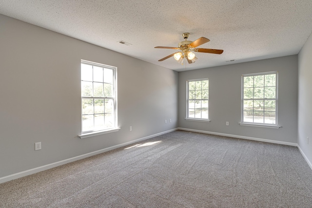 carpeted spare room with a textured ceiling, baseboards, and visible vents
