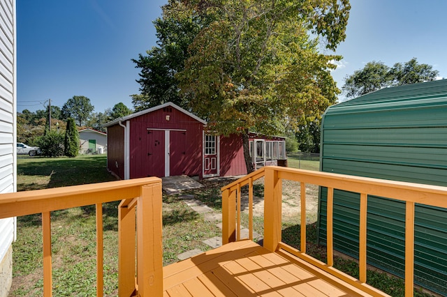 wooden deck featuring an outbuilding, a storage unit, and a yard