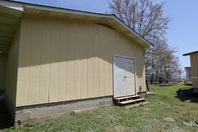 view of side of property featuring a yard, entry steps, and an outbuilding