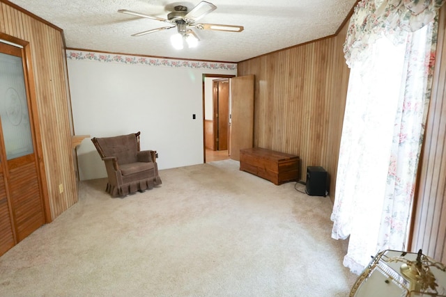 unfurnished room with wood walls, a textured ceiling, a ceiling fan, and ornamental molding