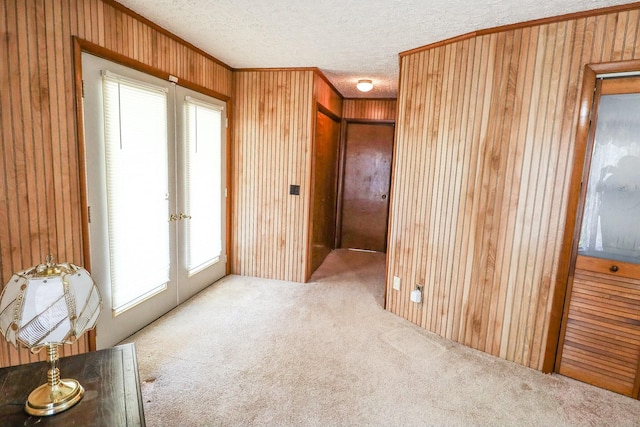 carpeted spare room with wood walls, a textured ceiling, crown molding, and a healthy amount of sunlight