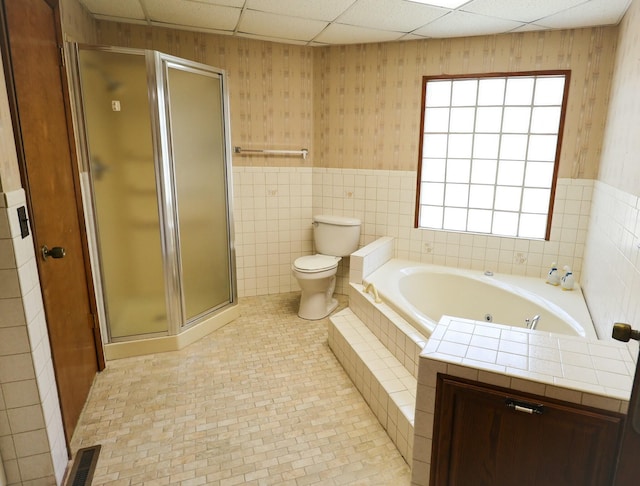 bathroom featuring toilet, a tub with jets, a healthy amount of sunlight, wallpapered walls, and a stall shower