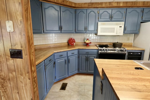 kitchen featuring white appliances, blue cabinets, light tile patterned flooring, wooden counters, and backsplash