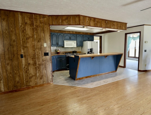 kitchen with backsplash, light wood finished floors, white appliances, and a textured ceiling