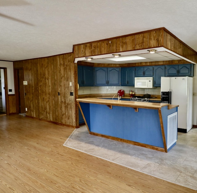 kitchen with tasteful backsplash, a breakfast bar, white appliances, wood walls, and blue cabinetry