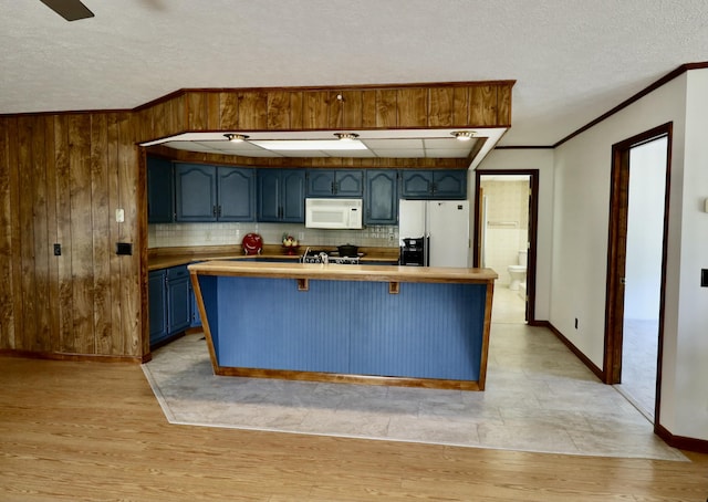 kitchen featuring white appliances, light wood-style flooring, a textured ceiling, and blue cabinetry