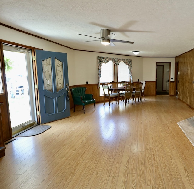 interior space featuring wood walls, light wood-style flooring, a textured ceiling, and ceiling fan