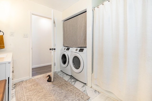 clothes washing area featuring laundry area, marble finish floor, baseboards, and separate washer and dryer