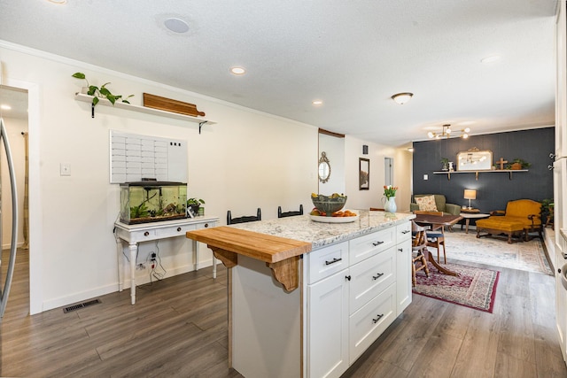 kitchen featuring a kitchen island, dark wood-style floors, white cabinetry, and visible vents