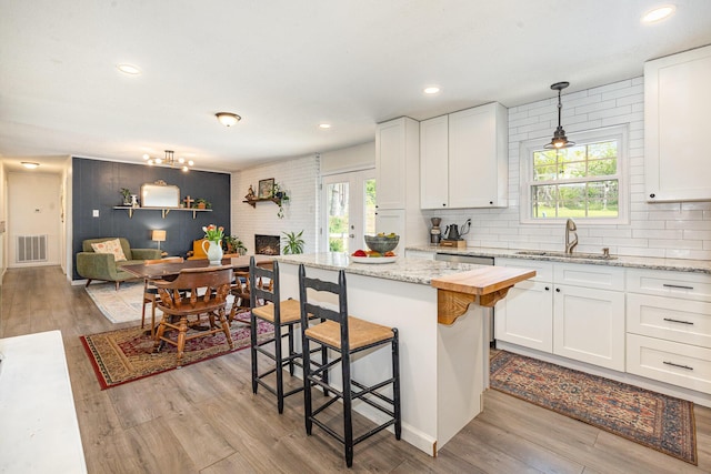 kitchen featuring white cabinetry, visible vents, a wealth of natural light, and a sink