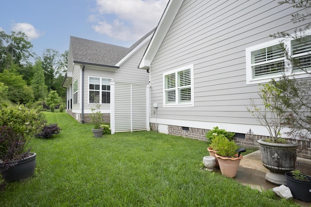 view of side of home featuring crawl space, roof with shingles, and a yard