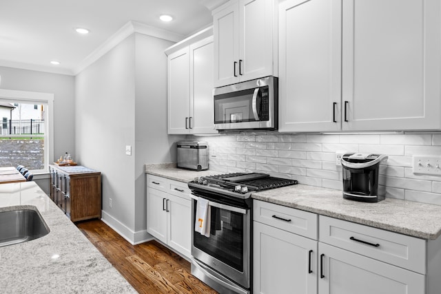 9876 Trestle Cir, Ooltewah, TN 37363 - kitchen with light stone counters, stainless steel appliances, ornamental molding, dark wood-style flooring, and white cabinetry