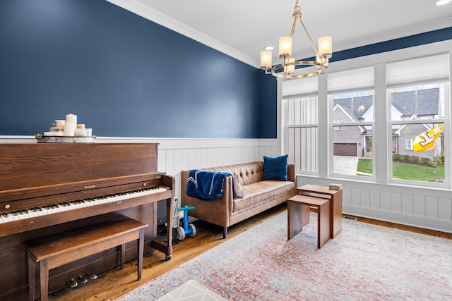 9876 Trestle Cir, Ooltewah, TN 37363 - living area featuring wood finished floors, a wainscoted wall, ornamental molding, and an inviting chandelier